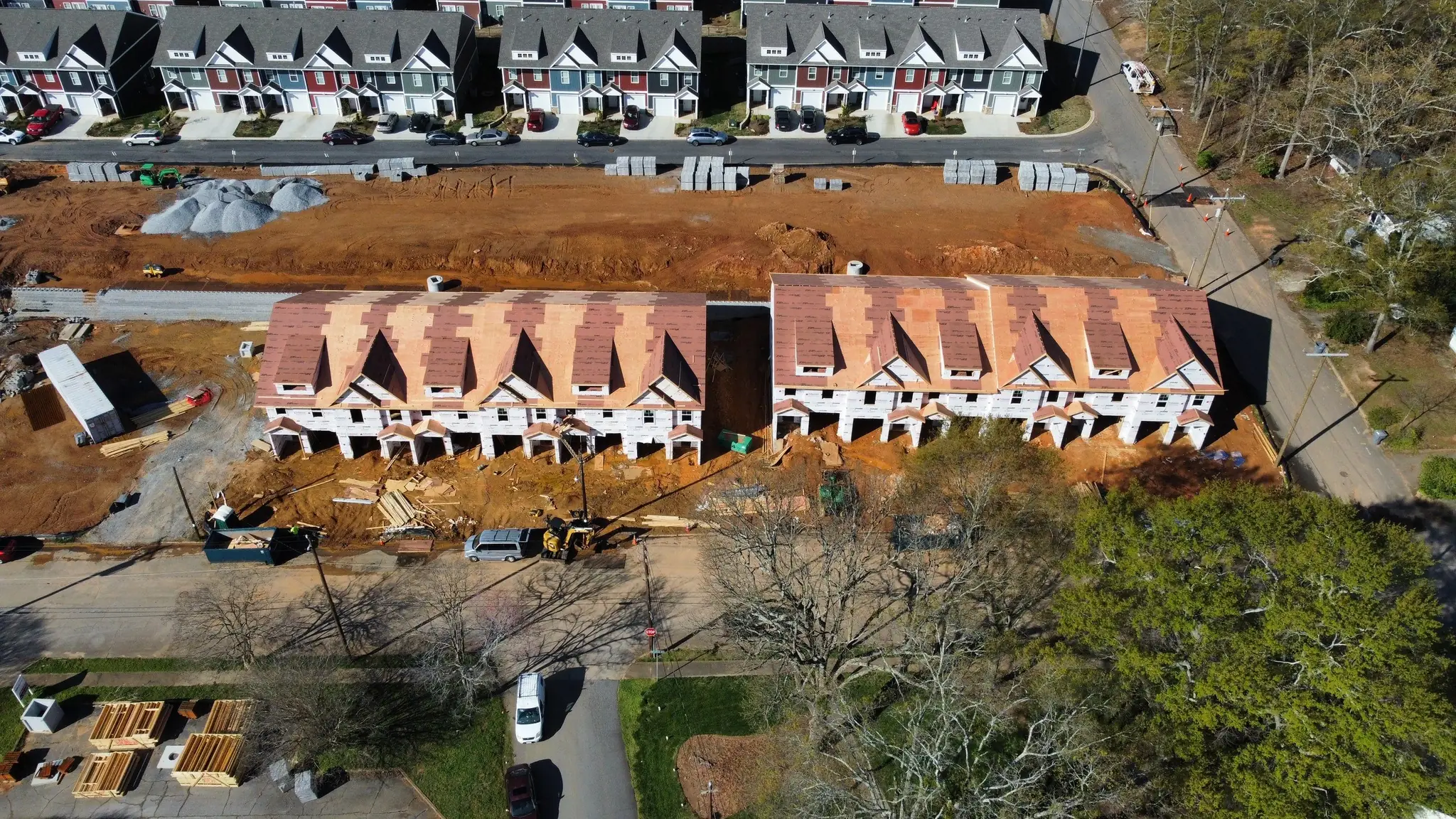 Aerial of a framed townhome row with roof shingles being installed